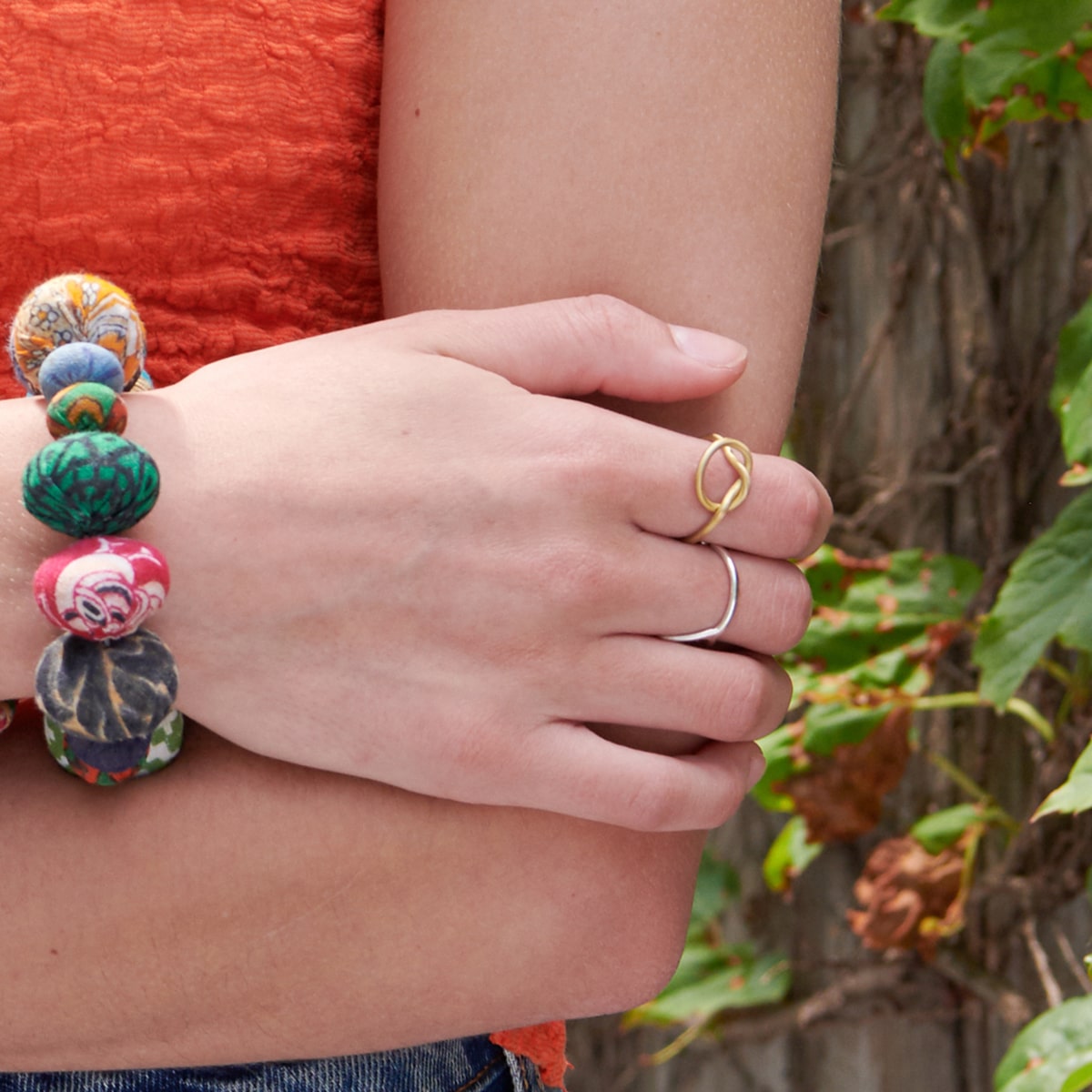 A woman rests her hand on her elbow, showing off her two rings on her fingers.