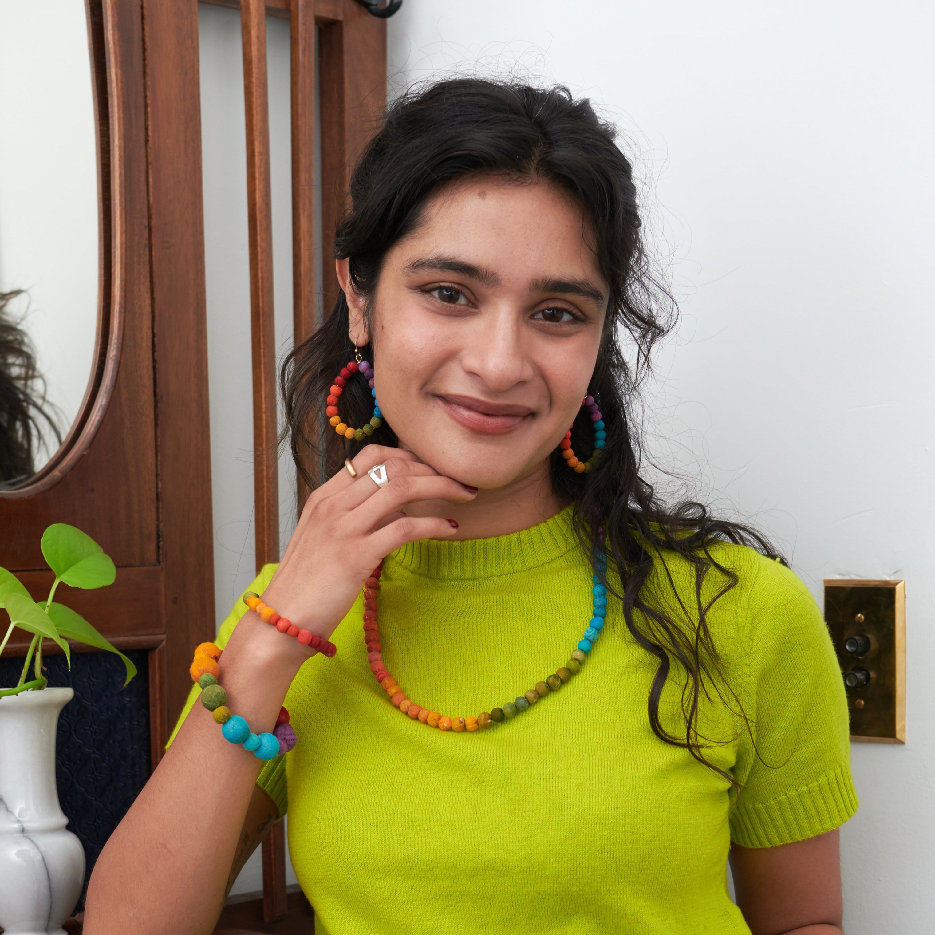 Model wearing the Kantha Prism Bracelets made of beads that have been sorted and arranged into vibrant, color-blocked sections for an multichromatic rainbow-like display of color.