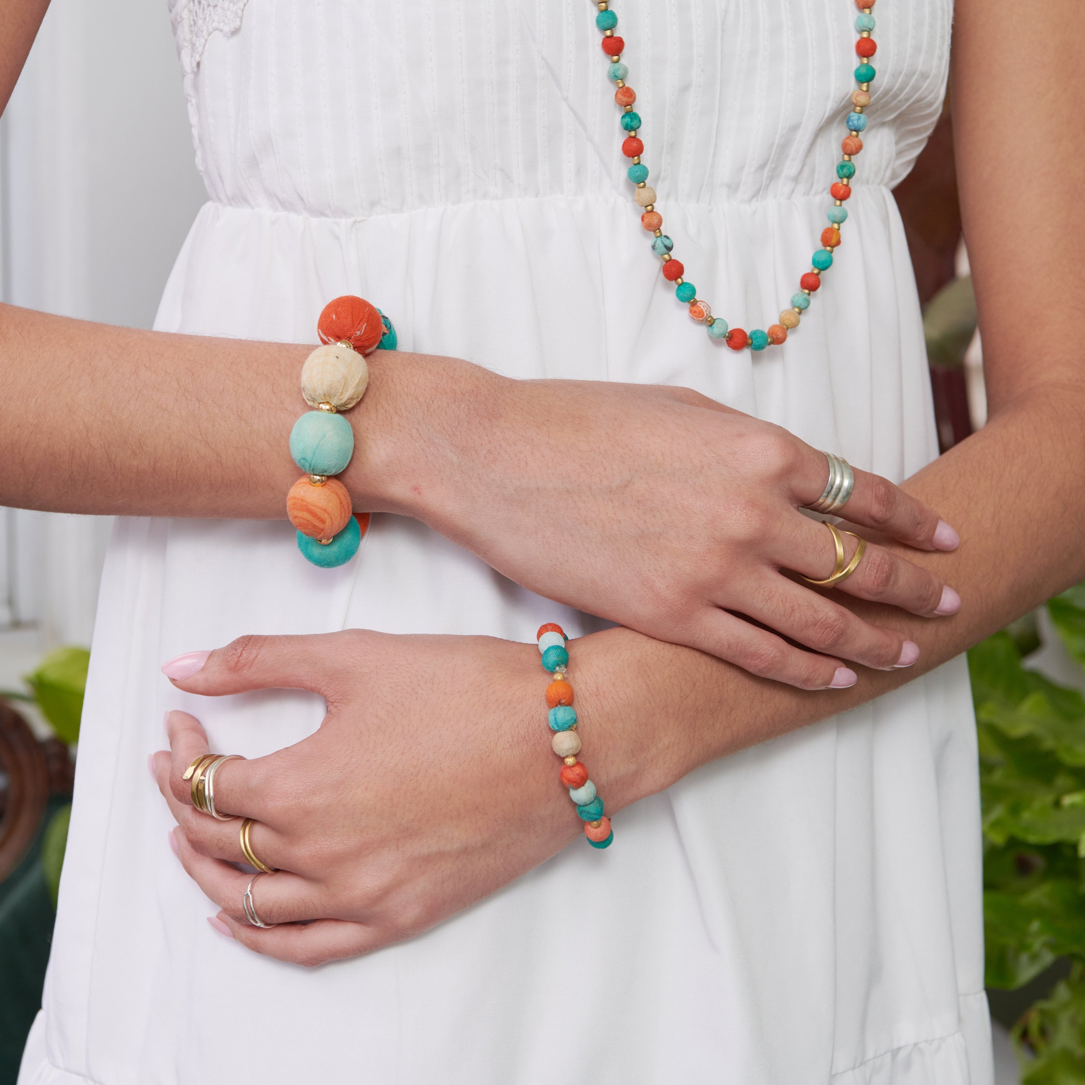 Model wearing the colorful  Kantha Capri Bracelets featuring groups of colorized Kantha beads separated by smaller metallic beads.