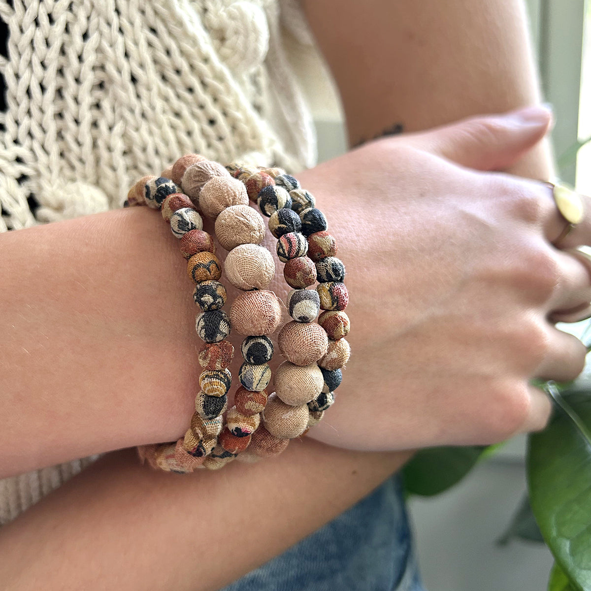 A close up of a woman's wrist and her beaded, neutral-toned bracelet.