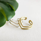 A gold ring rests on top of a silver ring against a white background with a green leaf in the background.