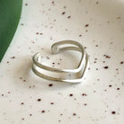 A silver ring rests on a white speckled surface.