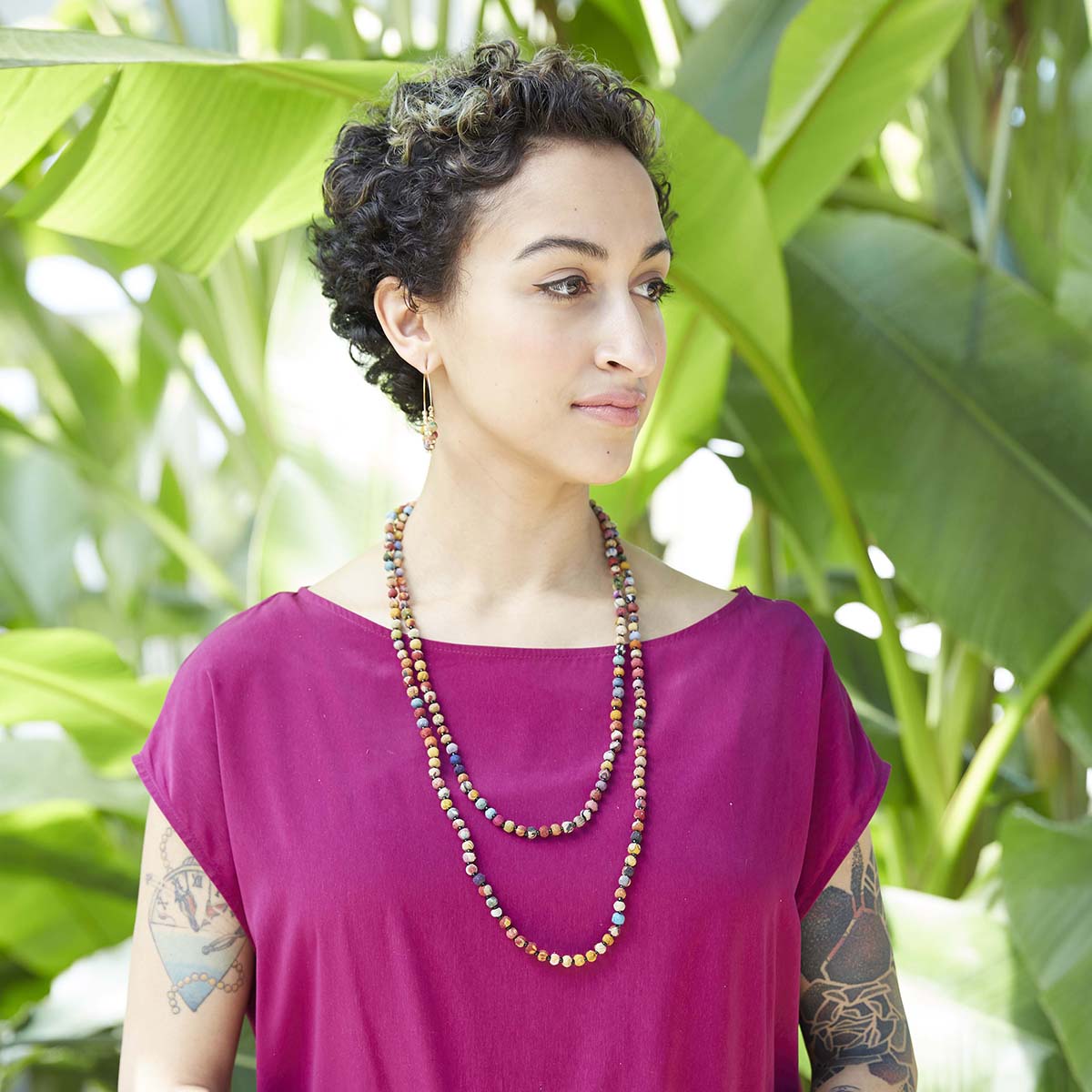 A woman in a pink shirt is adorned with a multicolored, beaded necklace.