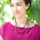 A woman in pink is adorned with multicolor, beaded jewelry.