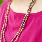 A close up of multicolor, beaded jewelry that alternates colorful fabric beads with small black seed beads.