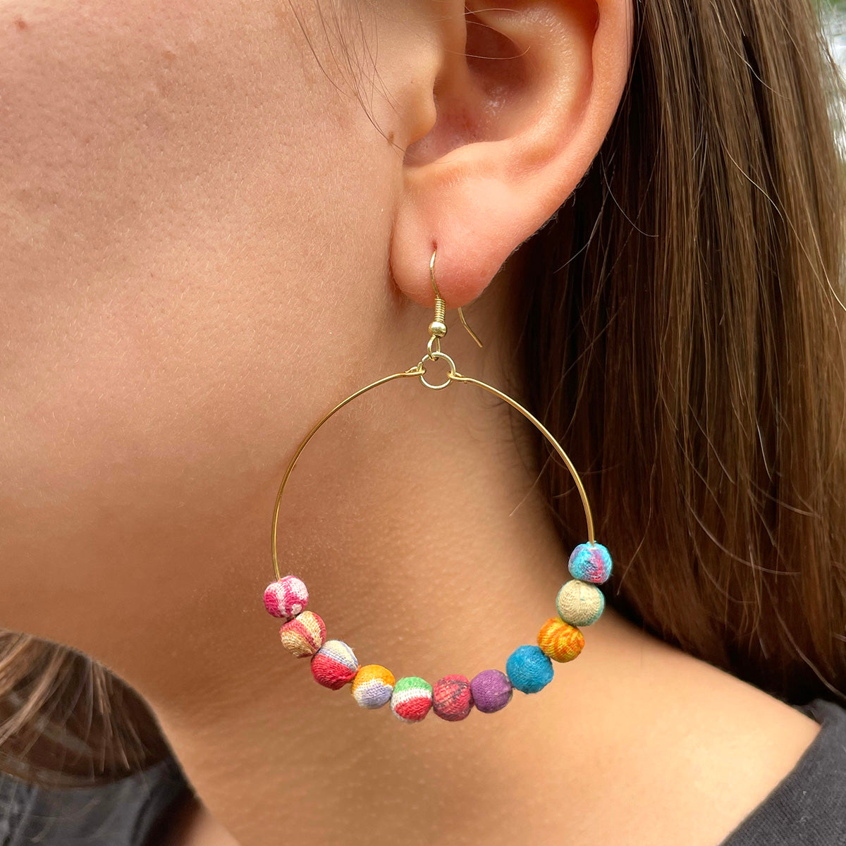 A close up of a woman's multicolored, beaded earring.