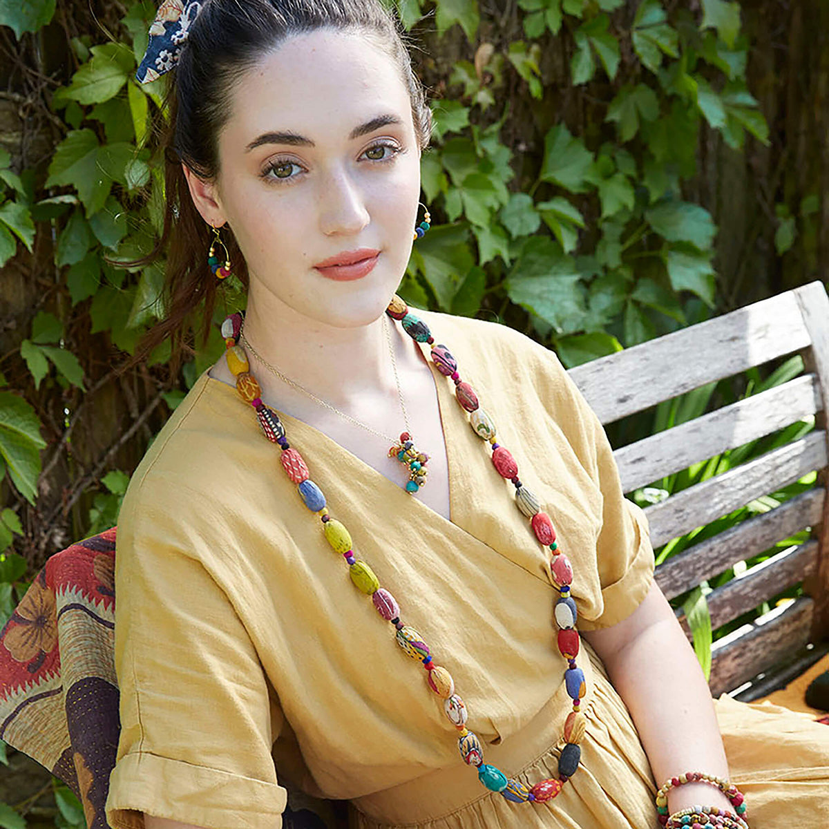 A woman in a yellow dress and multicolor beaded jewelry.