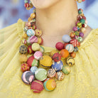 A close up image of a woman's necklace, which is multicolored, layered and beaded.
