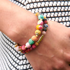 A close up of a woman's wrist and the two multicolor beaded bracelets she wears.