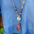A close up of a woman's blue shirt and the multicolor beaded necklace she is wearing.