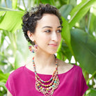 A woman wears the Kantha Ornamental Chandeliers.