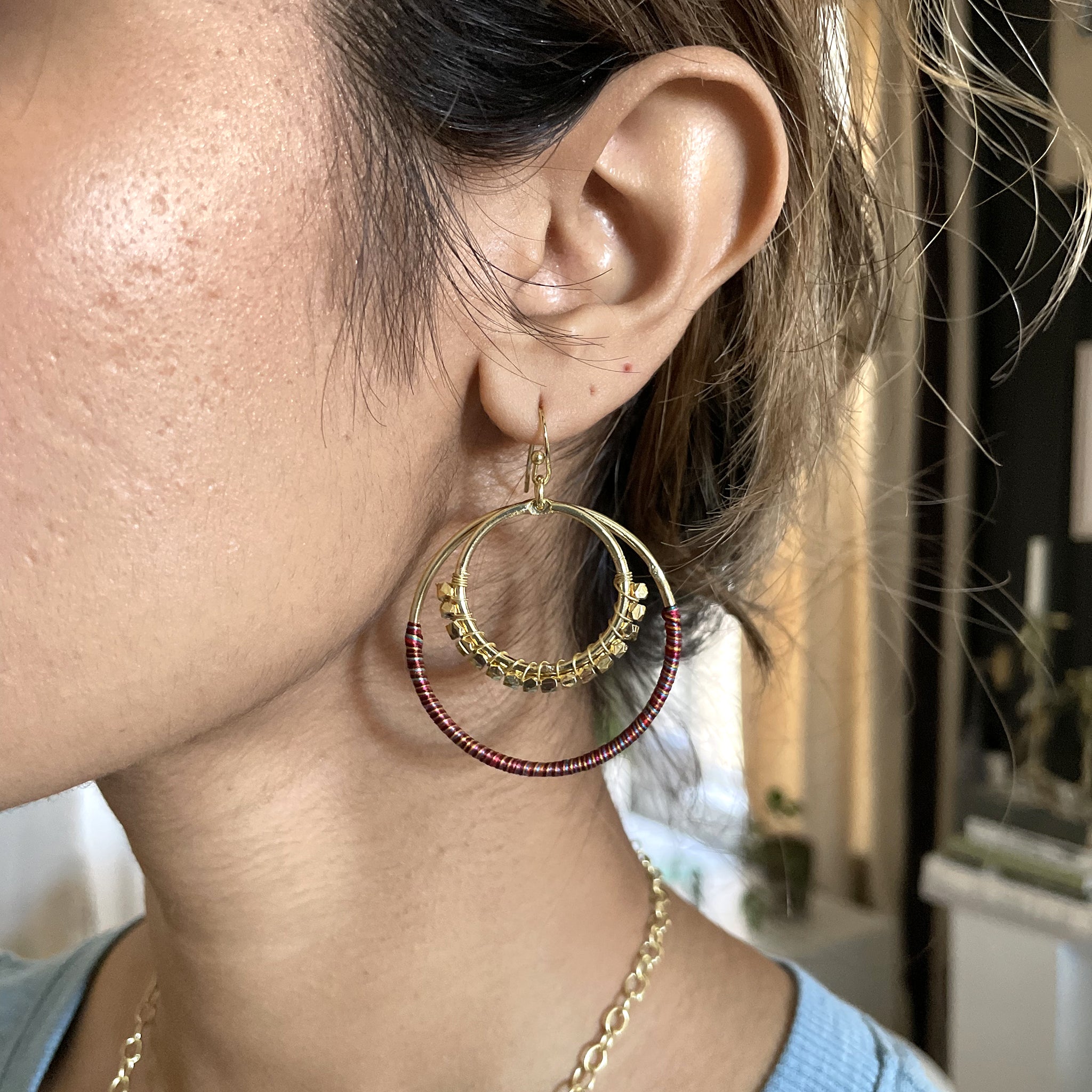 A close-up of a woman's ear while wearing the Raja Sunrise Hoops.