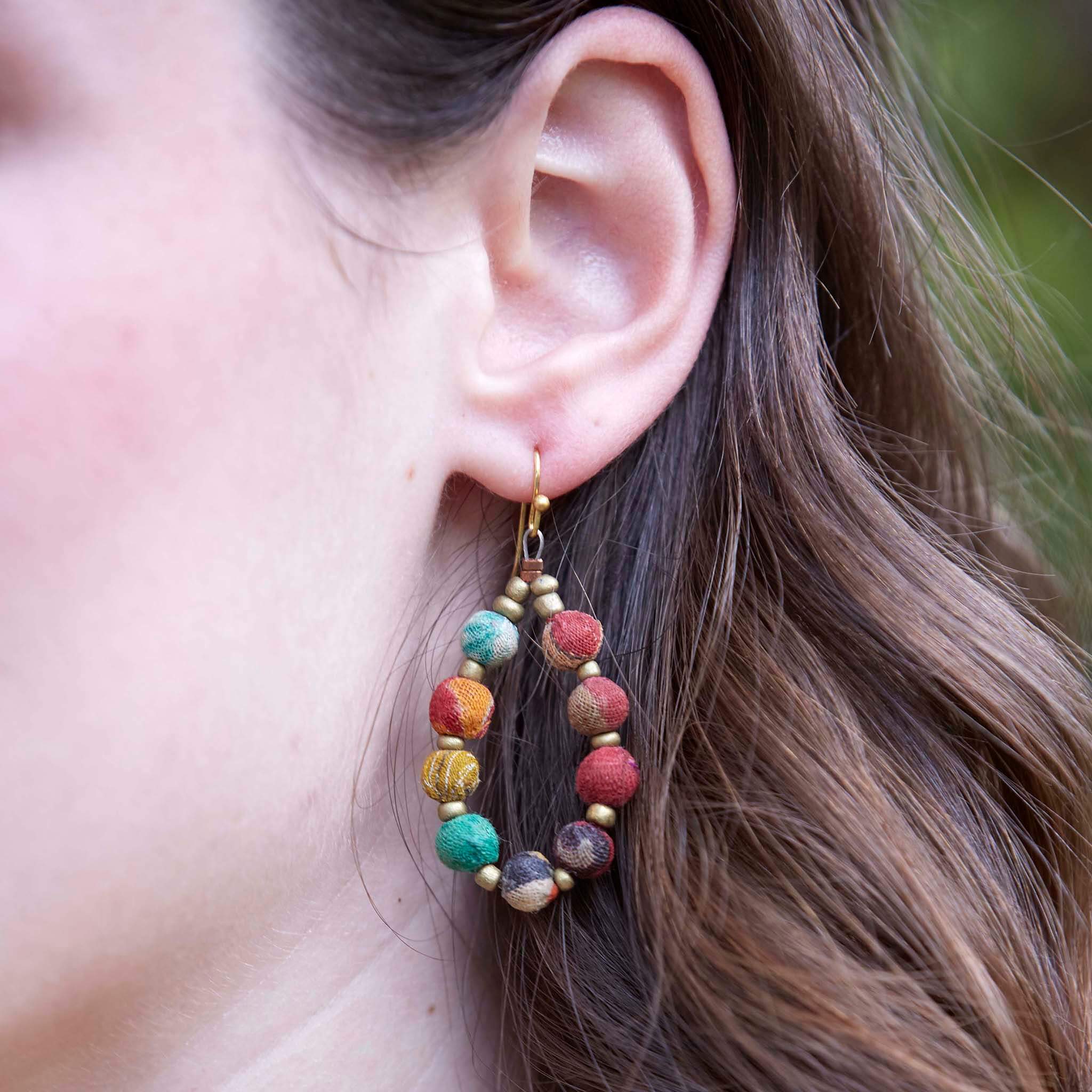 A close-up of a woman's multicolor, beaded teardrop earring.