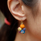 A close-up of a woman's ear and the multicolor, beaded earring she is wearing.