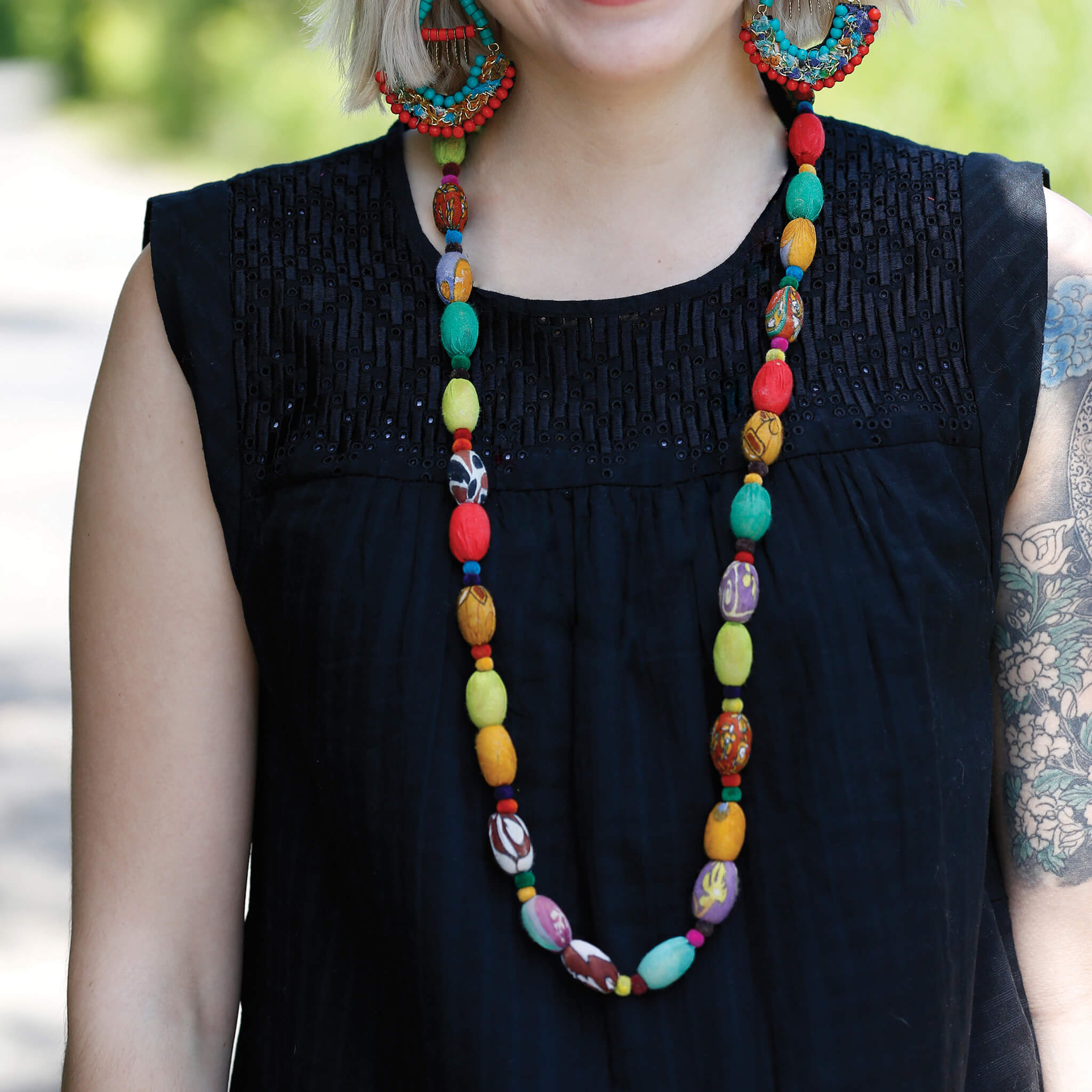 A woman in a black shirt and a long multicolored, beaded necklace.