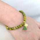 A close up of a woman's wrist and the green beaded bracelet she wears.
