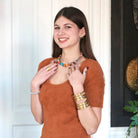 A woman smiles at us while modeling jewelry.