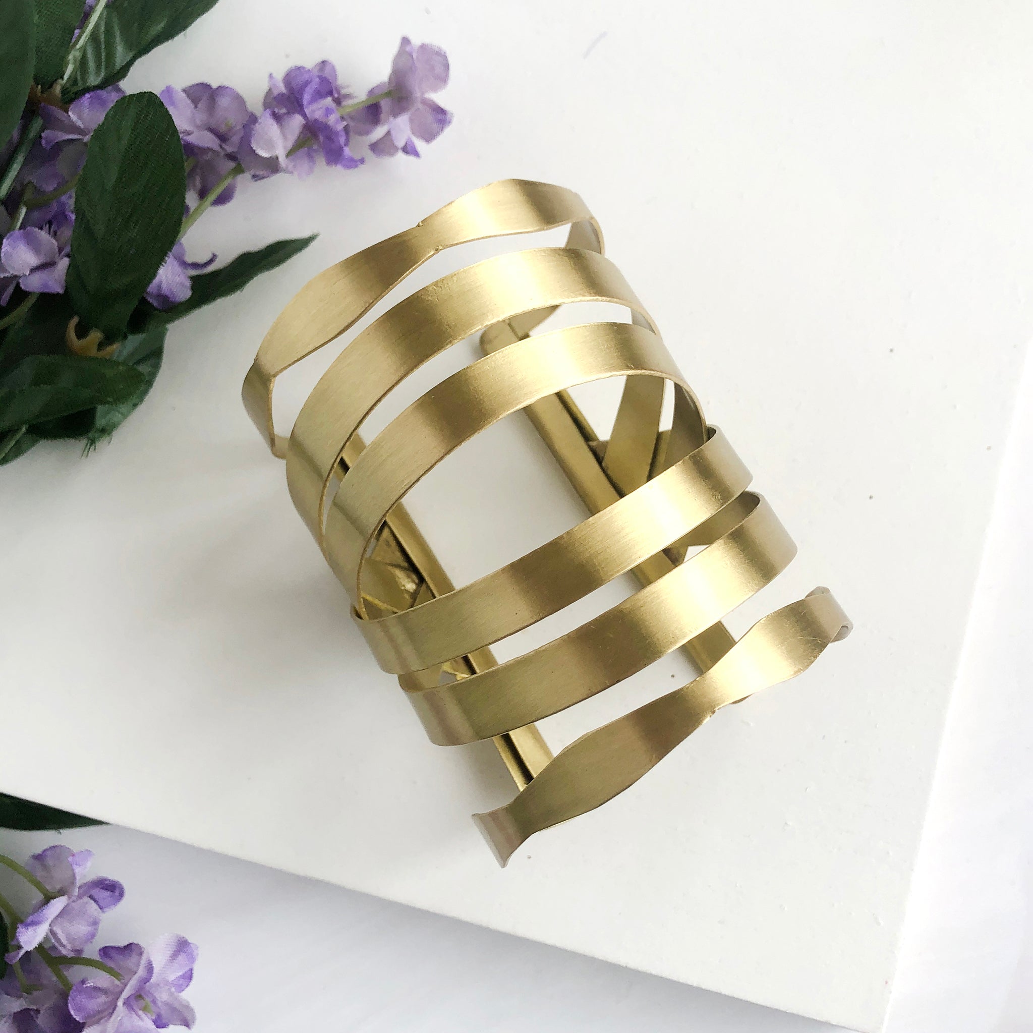 Six metal bands arch and crisscross to form a gold cuff bracelet.