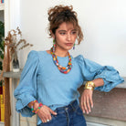 A woman models colorful beaded jewelry and a large gold cuff.