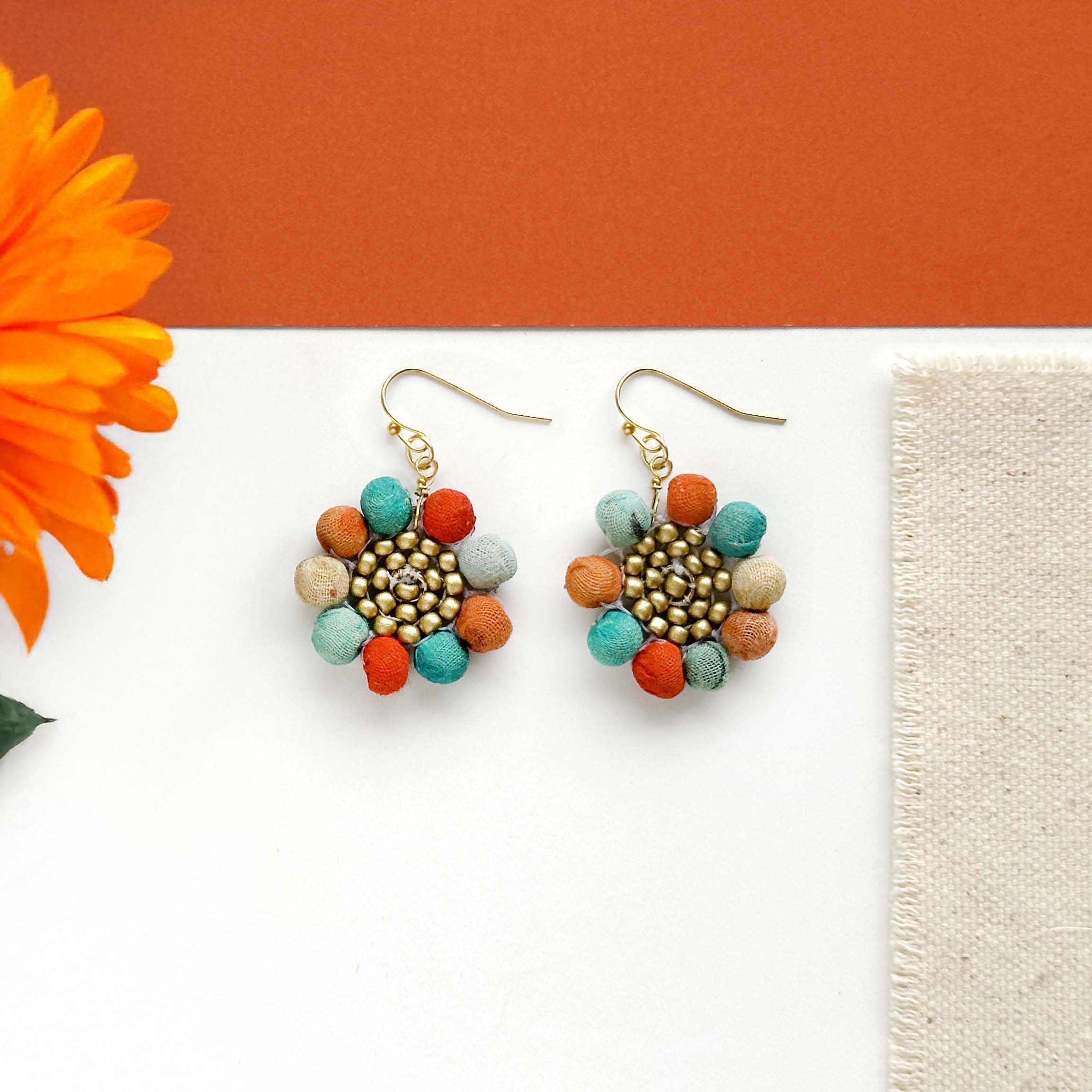 Kantha beads surround a circle of matte gold seed beads in a playful flower shape to form the Kantha Capri Sunflower Earrings. 