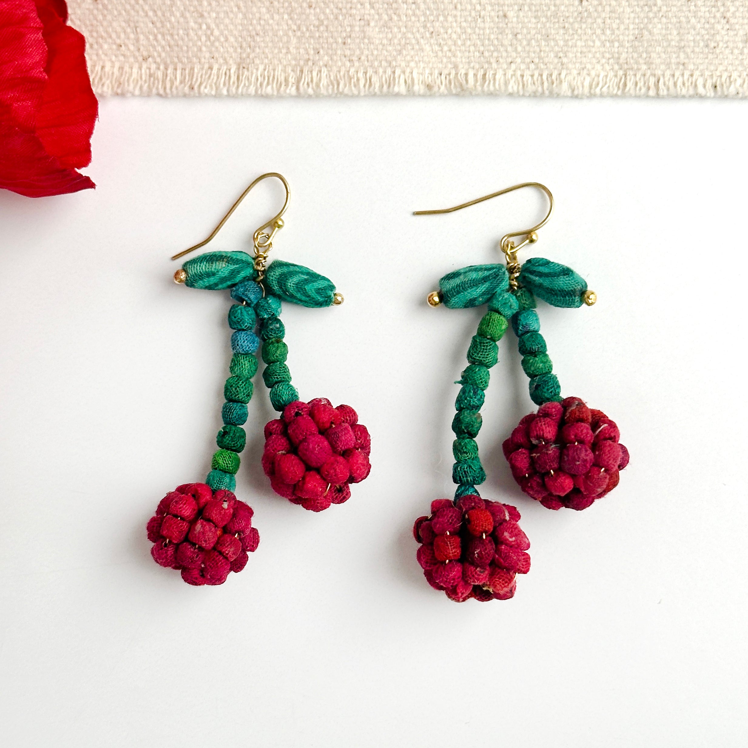 Teeny tiny Kantha fabric beads in cherry red have been crafted into a pair of your favorite fruit, that dangle from green stems.