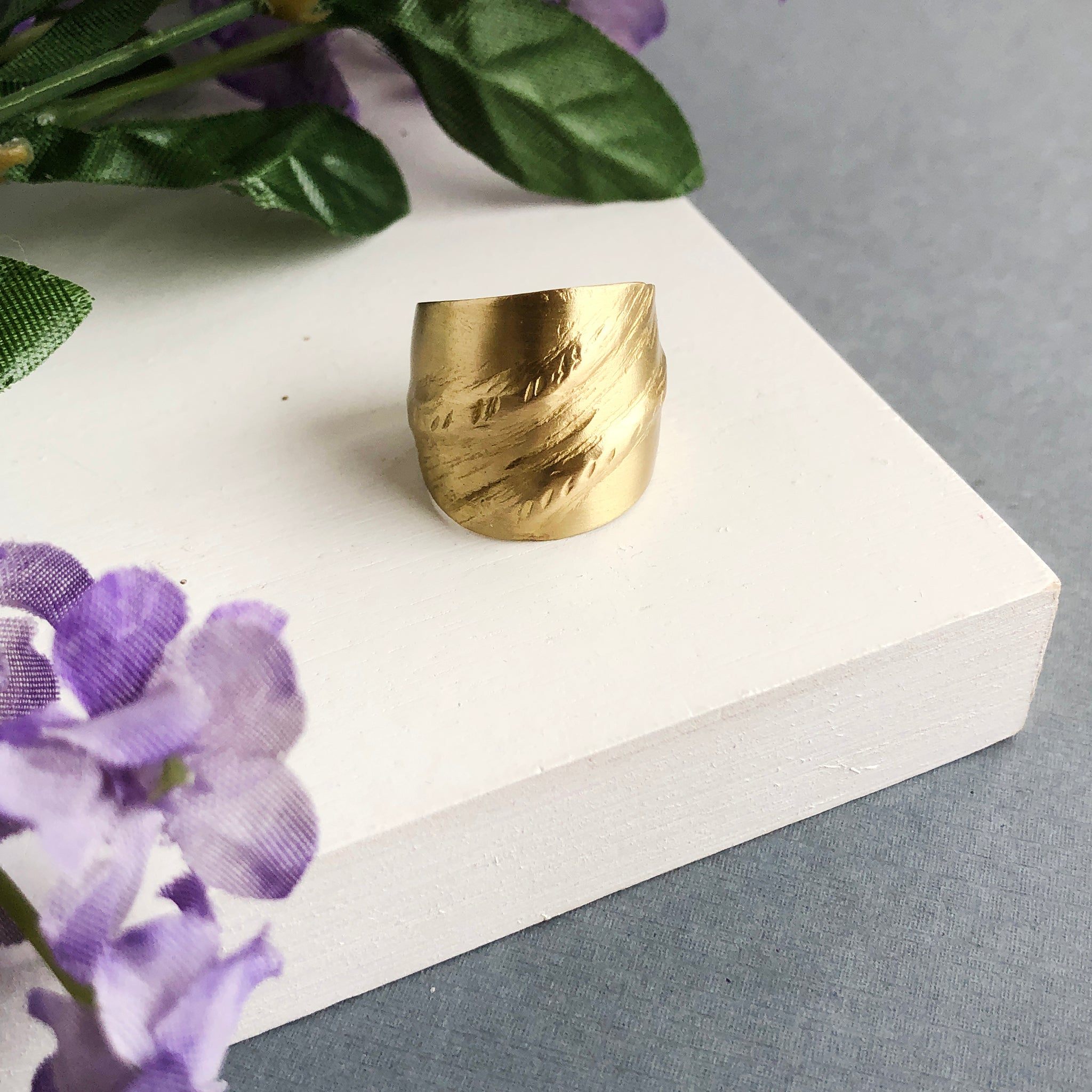 A single gold statement ring features diagonal textures.