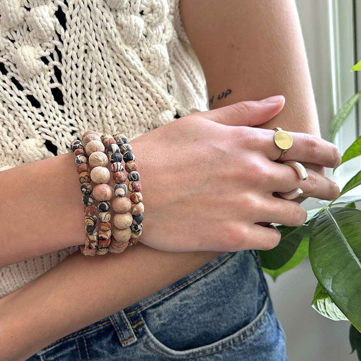 A woman's hand rests on her elbow, showing off her gold and silver rings.