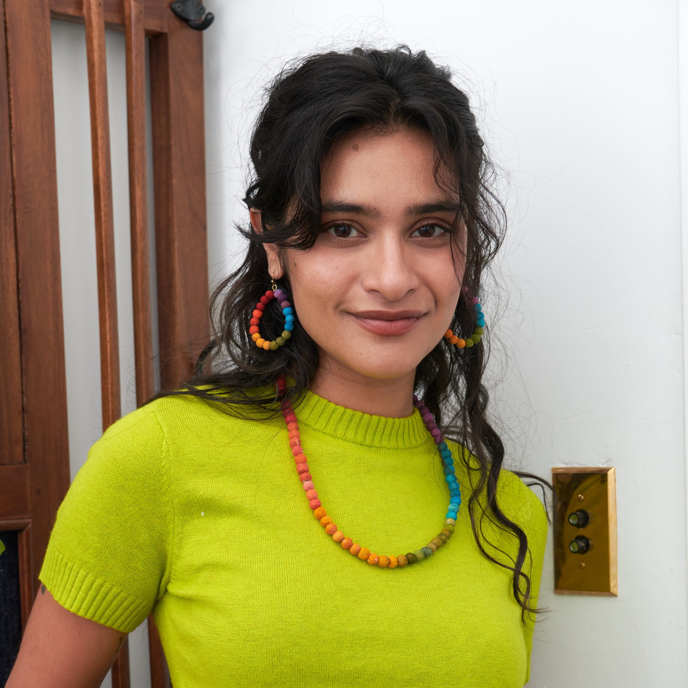 Model wearing Kantha Prism Collection made of beads that have been sorted and arranged into vibrant, color-blocked sections for an multichromatic rainbow-like display of color.
