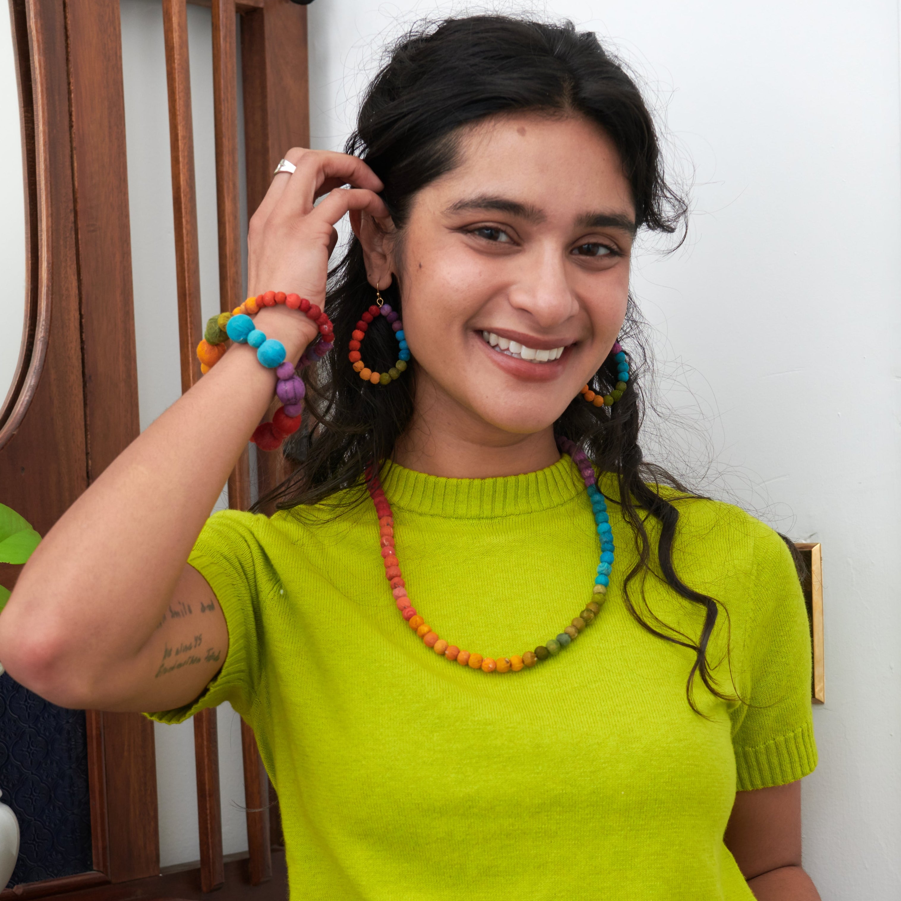 Model wearing Kantha Prism Collection made of beads that have been sorted and arranged into vibrant, color-blocked sections for an multichromatic rainbow-like display of color.
