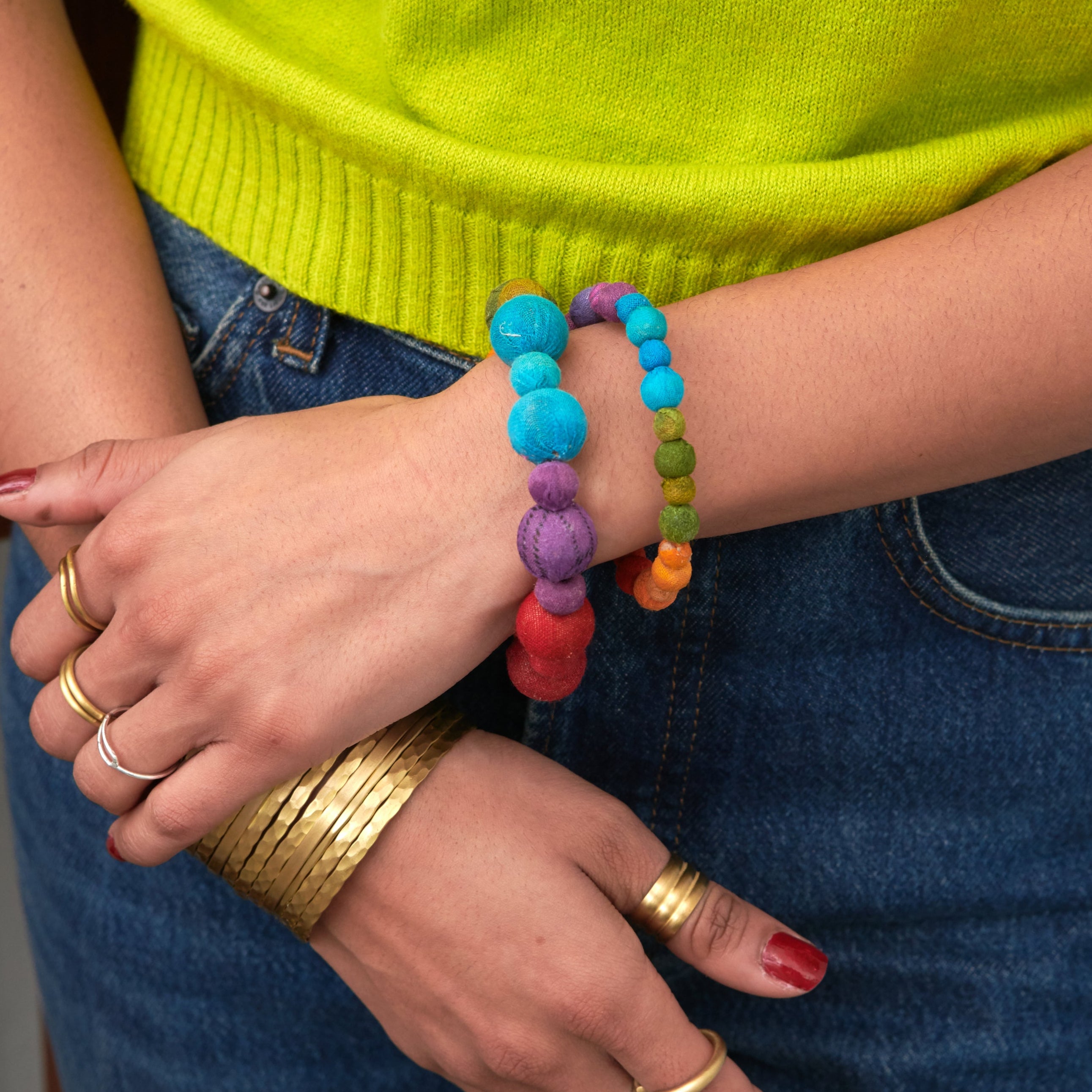Model wearing the Kantha Prism Bracelets made of beads that have been sorted and arranged into vibrant, color-blocked sections for an multichromatic rainbow-like display of color.
