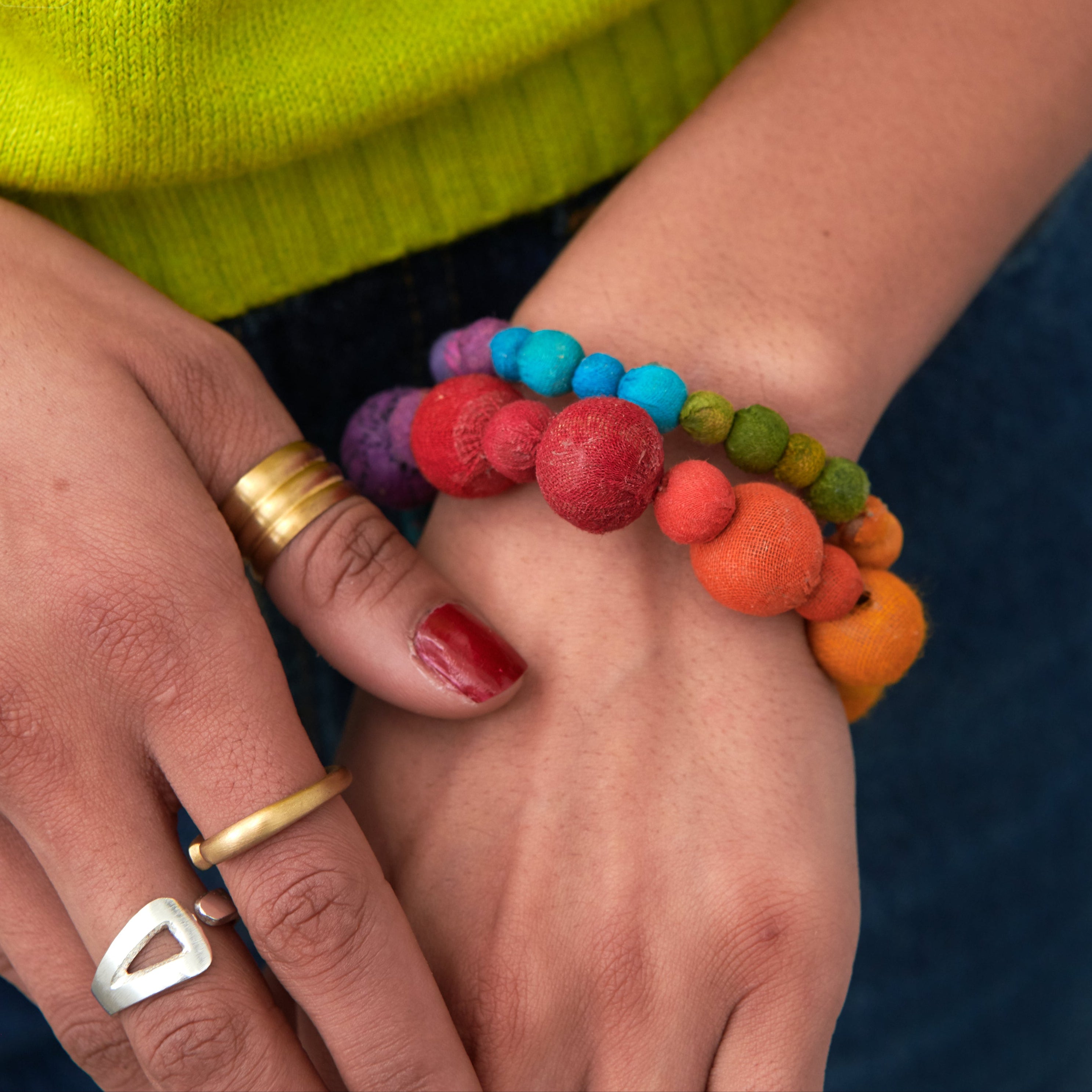 Model wearing the Kantha Prism Bracelets made of beads that have been sorted and arranged into vibrant, color-blocked sections for an multichromatic rainbow-like display of color.
