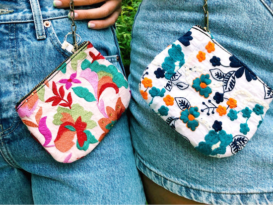 Two floral change purses clipped to women's denim shorts