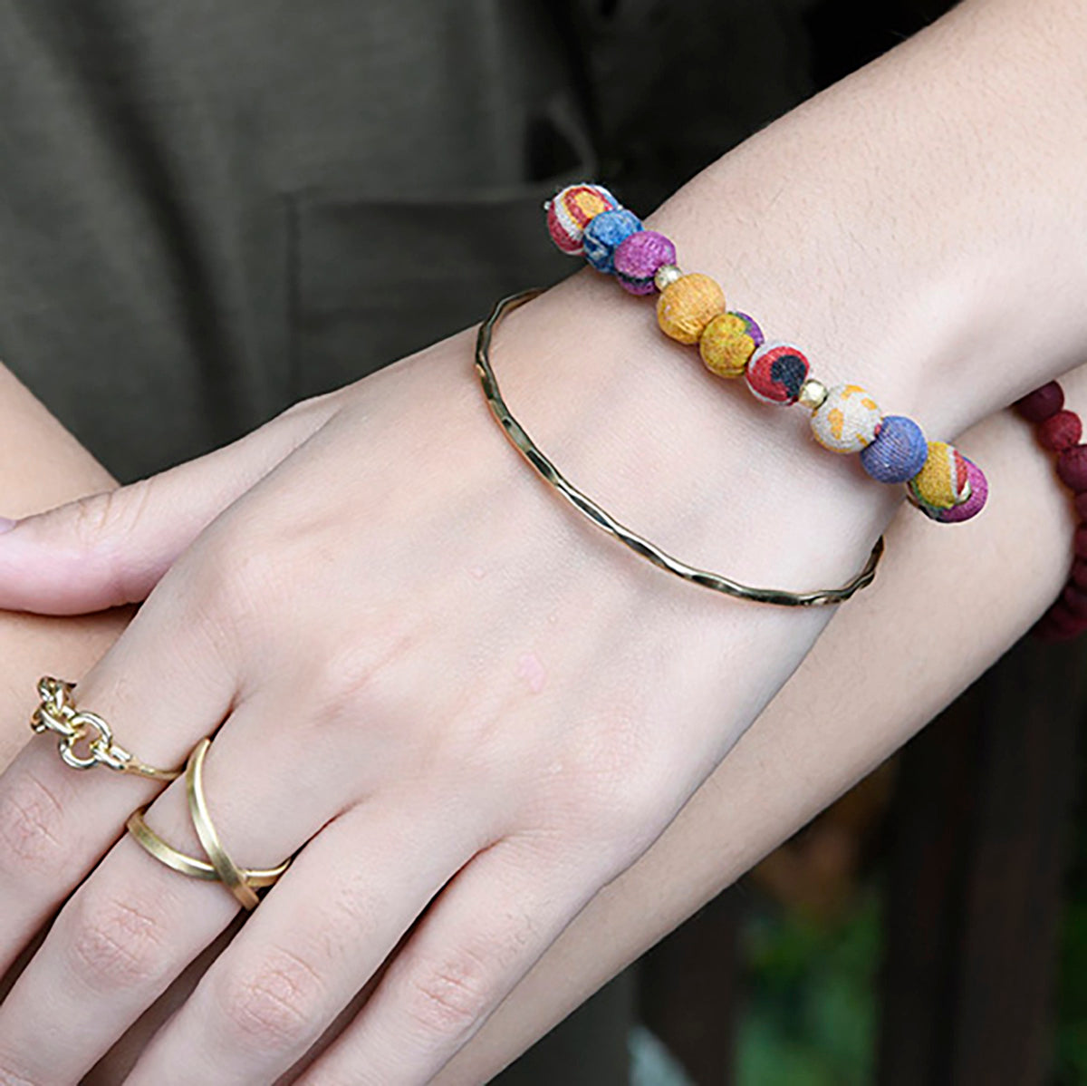 A close up of a woman's wrist resting on her other arm, and her bracelets she is wearing.