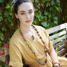 A woman in a yellow dress and multicolor beaded jewelry.