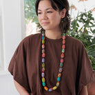 A young woman in a brown shirt and multicolored, beaded jewelry.
