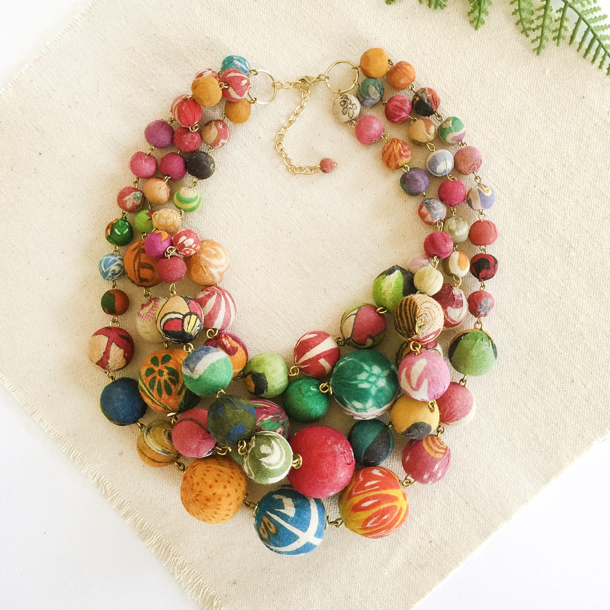 A mulitcolored, beaded necklace on a tan background.