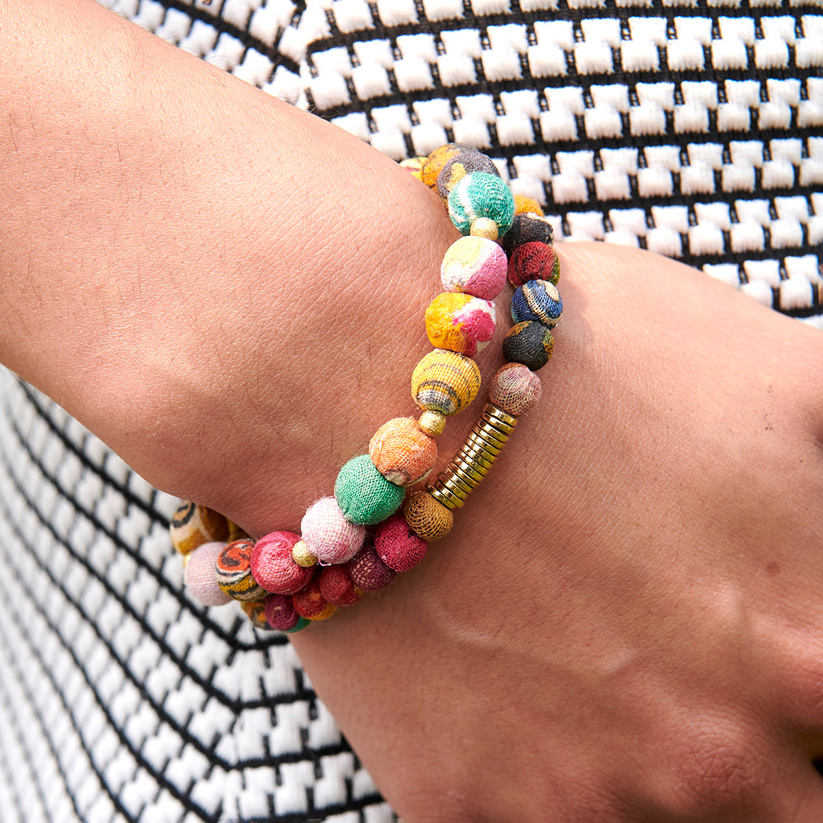 A close up of a woman's wrist and the two multicolor beaded bracelets she wears.