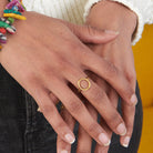 A close up of a woman's hand and her gold metal ring.