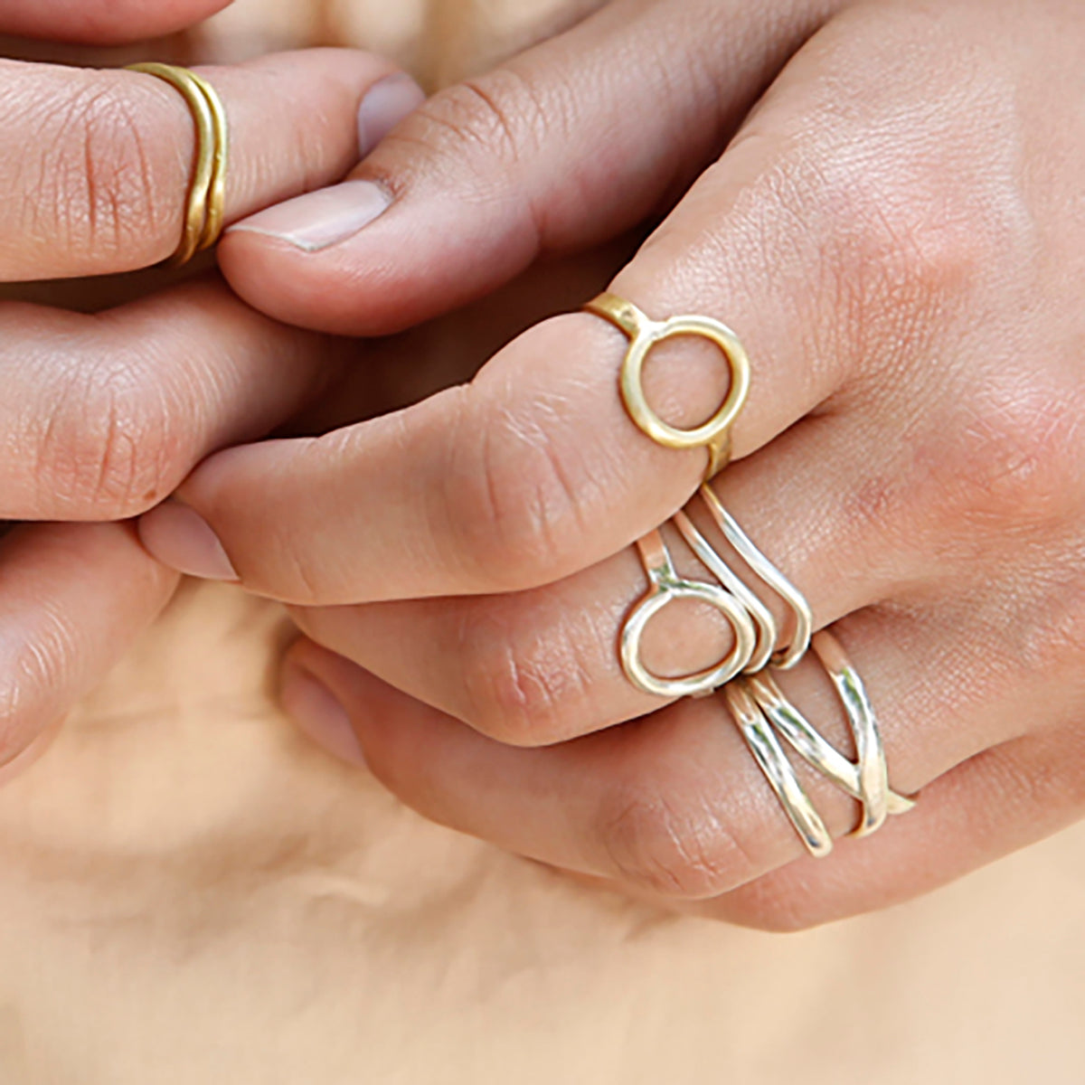 A close up of the metallic rings on a woman's fingers.