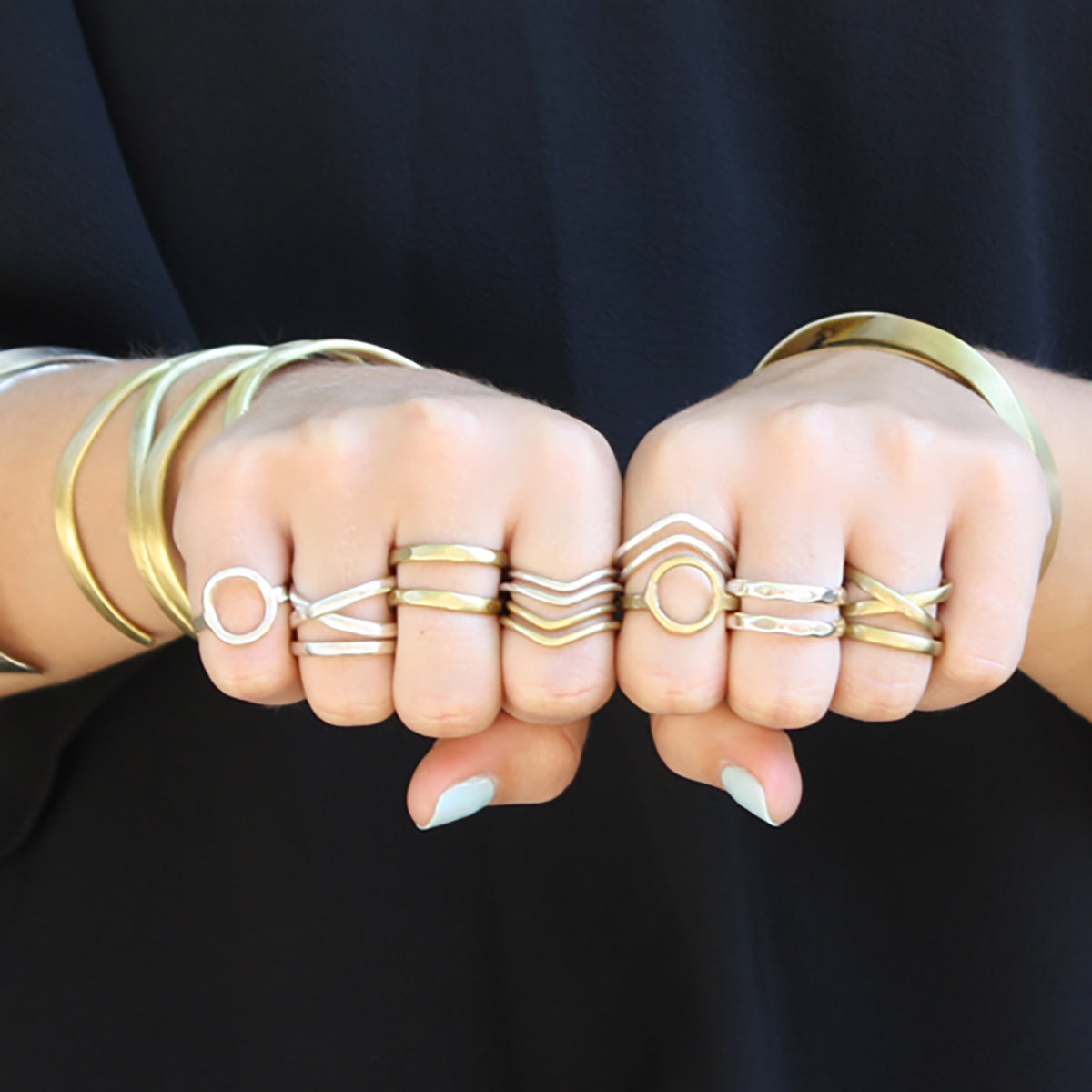 A close up of the metallic rings on a woman's fingers.