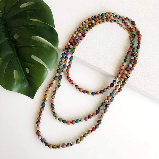 A long strand of small multicolored textile beads is looped thrice for a layered effect.