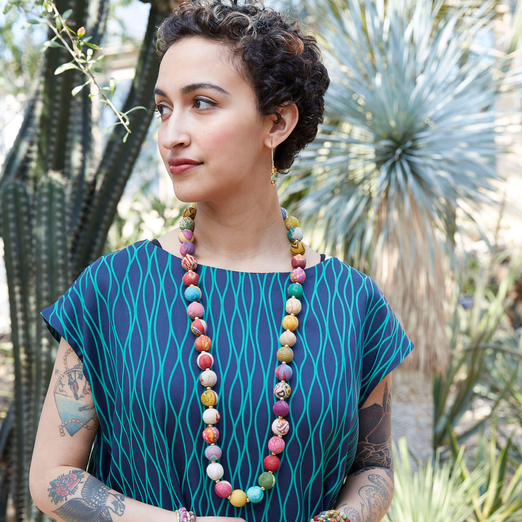 A woman with a patterned blue shirt wears the Kantha Garland Necklace.