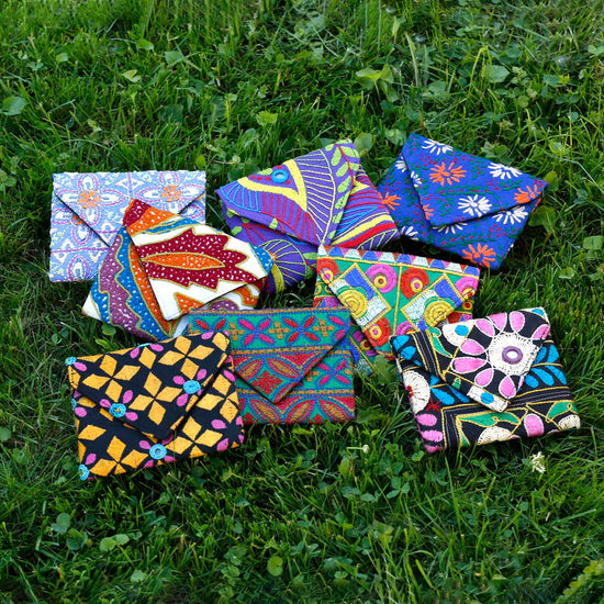 Load image into Gallery viewer, A collection of colorful Kutch Mini Pouches is displayed in green grass.
