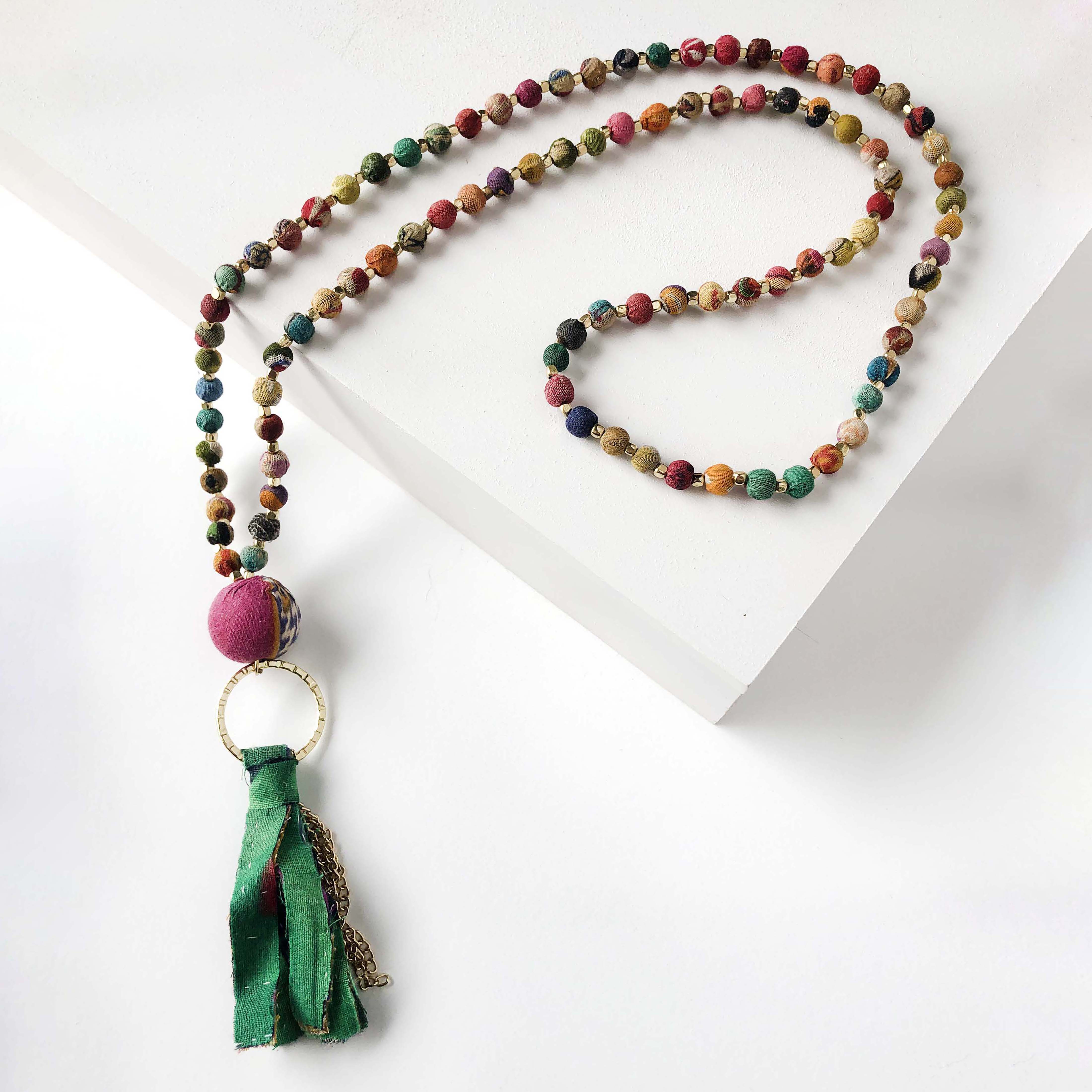 A strand of colorful textile-covered beads is punctuated with a statement bead and a colorful metallic-accented tassel.