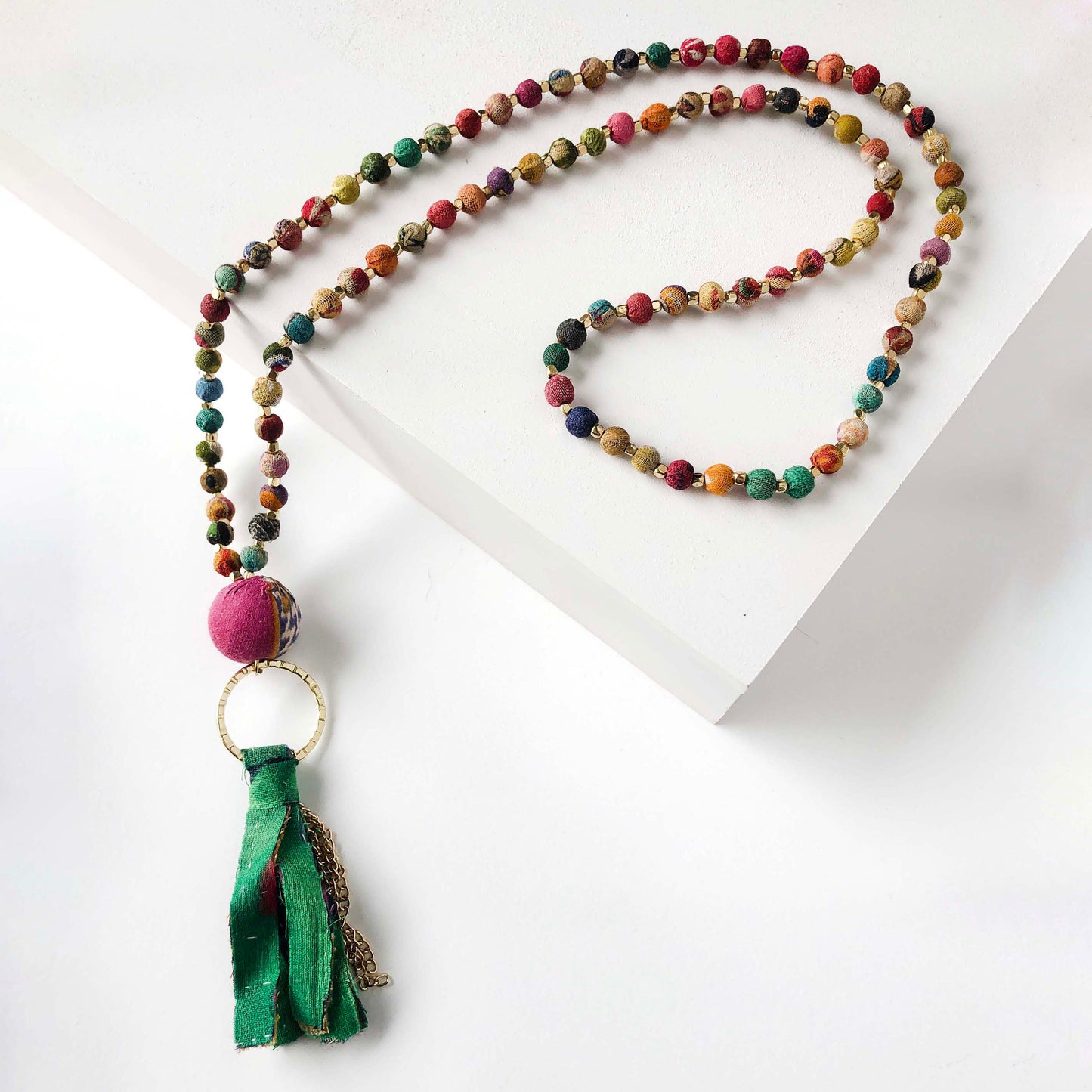Load image into Gallery viewer, A strand of colorful textile-covered beads is punctuated with a statement bead and a colorful metallic-accented tassel.
