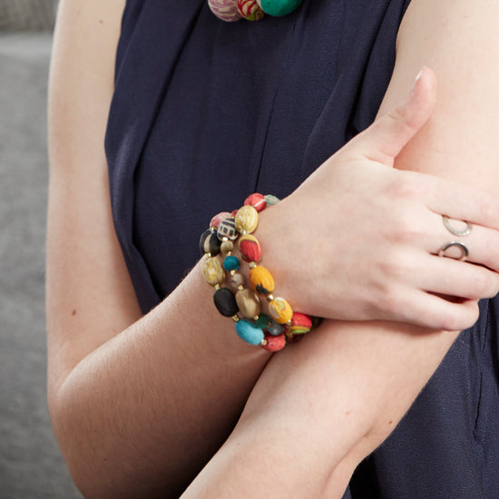 Multiple colorful beaded bracelets adorn a woman's wrist.