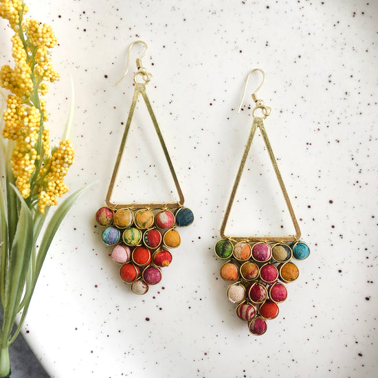 Load image into Gallery viewer, A triangle made from textile-wrapped beads and gold wire hangs from a golden triangle frame to form these earrings.
