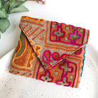 A multicolored envelope-style pouch features traditional embroidery techniques.