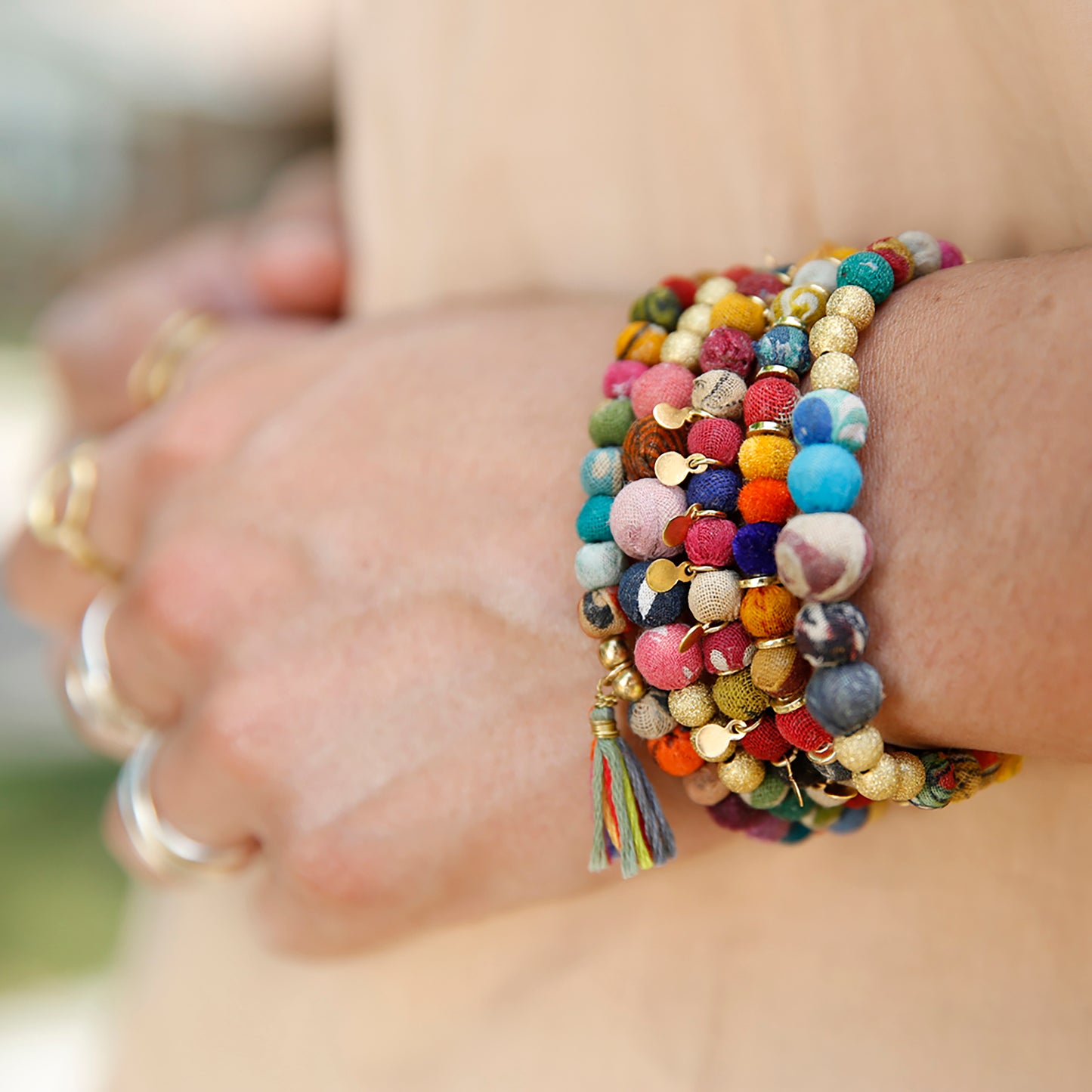 Load image into Gallery viewer, A stack of Kantha bracelets adorns a wrist.
