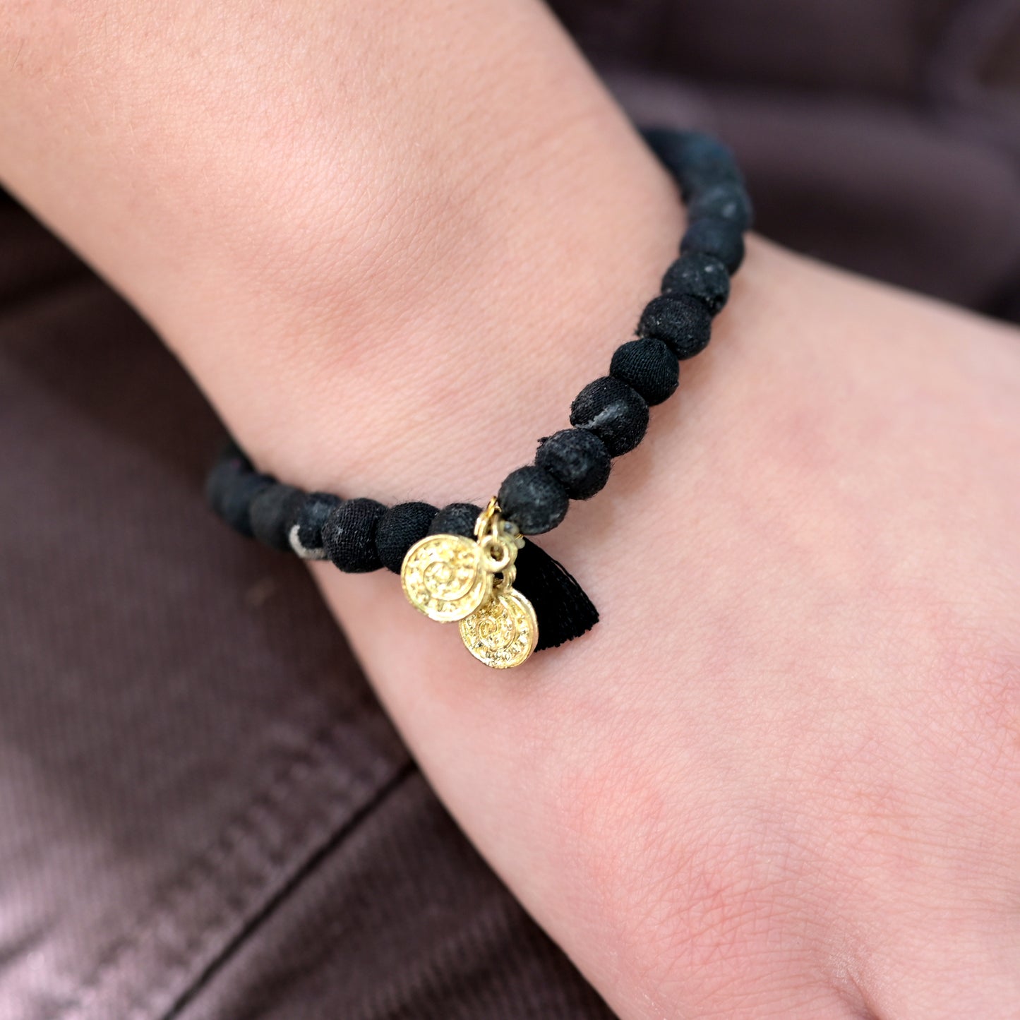 A black beaded bracelet adorns a wrist.